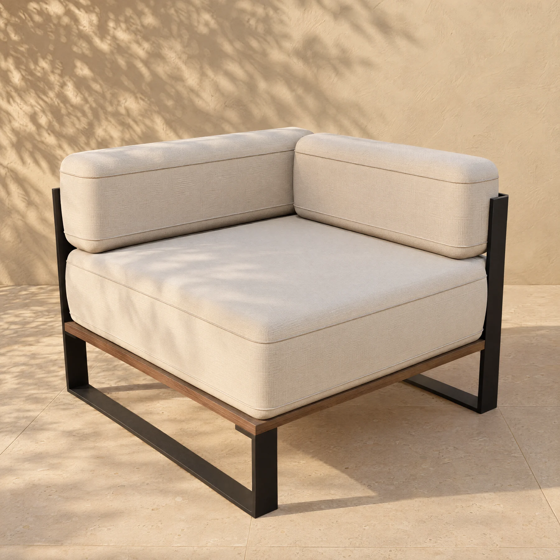 The Nour corner module alone on pale limestone paving before a warm plaster wall: the same thin black plate sleds and timber deck, one piped seat cushion, and two upright piped back pillows, the long one running into the corner and the short one butting against it.
